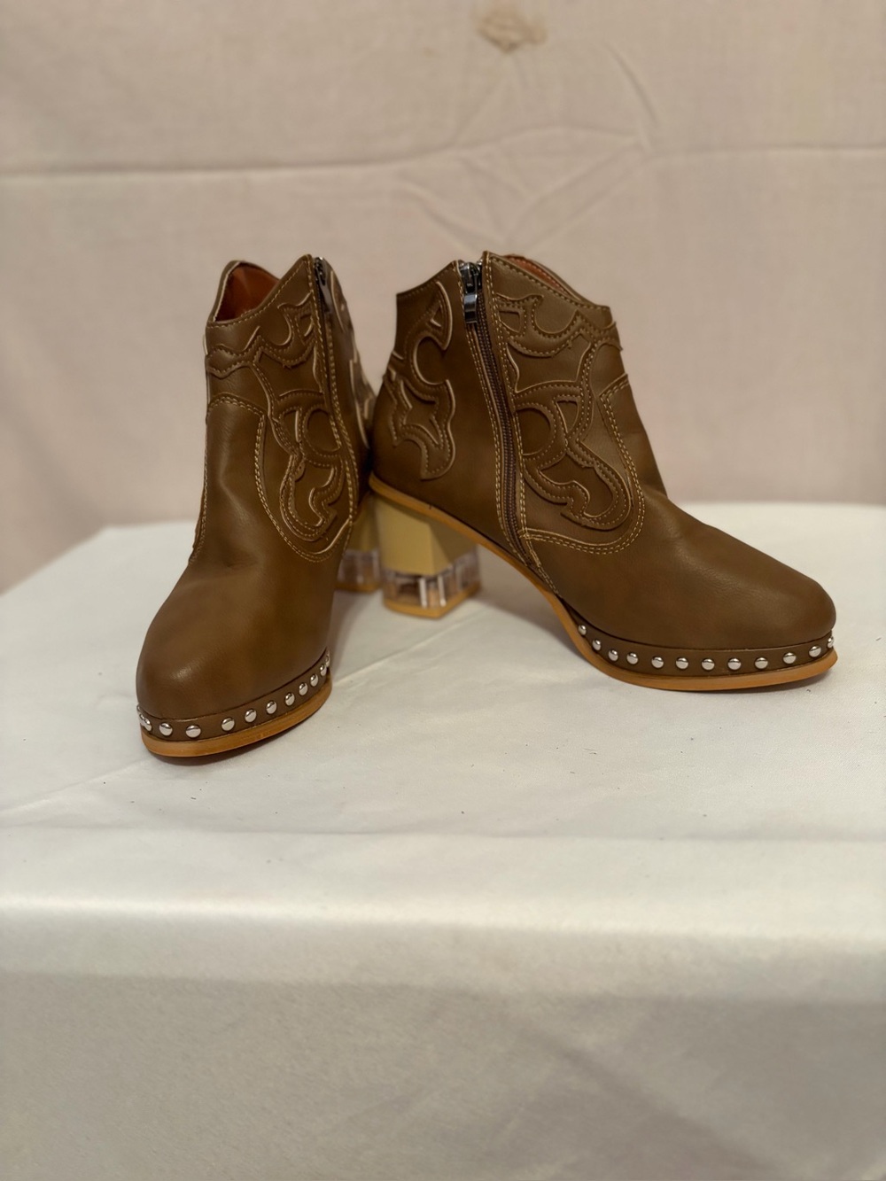 Brown ankle boots feature embroidered vintage designs and studded details